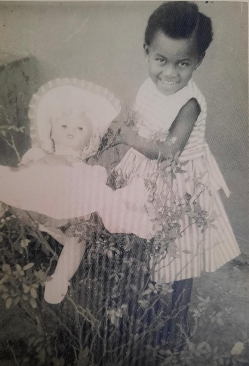 As a little girl, holding her doll.